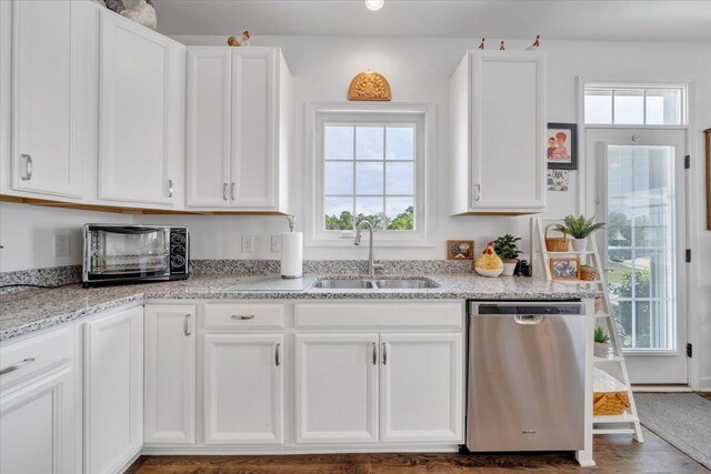 kitchen with stainless steel dishwasher, white cabinets, a sink, and a toaster