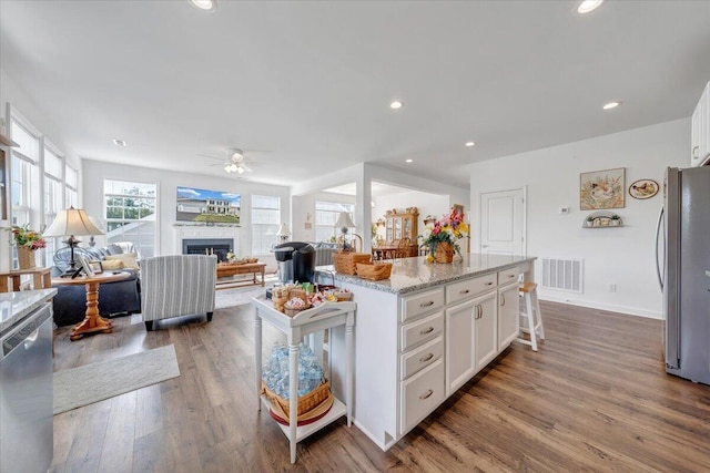 kitchen featuring ceiling fan, dark wood-style flooring, appliances with stainless steel finishes, open floor plan, and white cabinetry