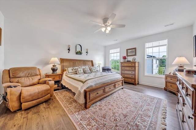 bedroom featuring baseboards, ceiling fan, wood finished floors, and visible vents