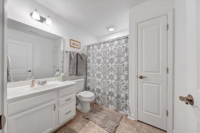 bathroom featuring toilet, a shower with curtain, visible vents, and vanity