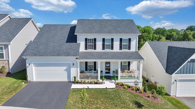 traditional-style home featuring a porch, an attached garage, a front yard, and aphalt driveway