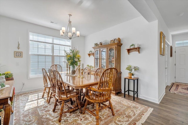 dining room with baseboards, visible vents, wood finished floors, and a notable chandelier