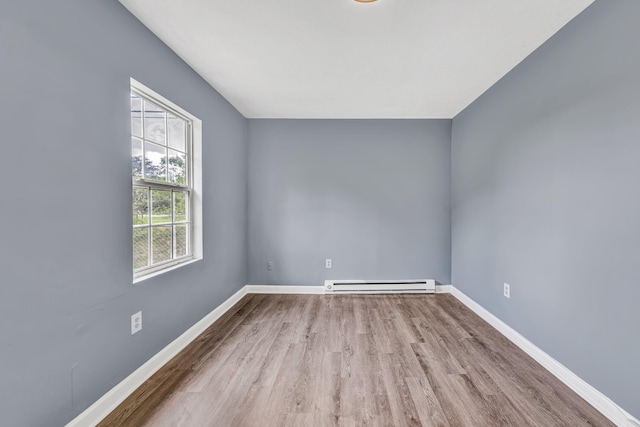 spare room featuring a baseboard radiator, wood finished floors, and baseboards