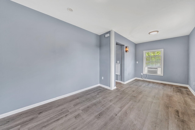 unfurnished room featuring wood finished floors, baseboards, and cooling unit