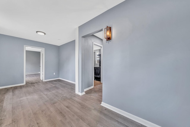 spare room with baseboards and wood finished floors