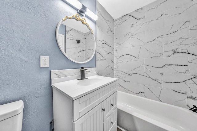 full bath featuring toilet, vanity, a textured wall, and shower / washtub combination