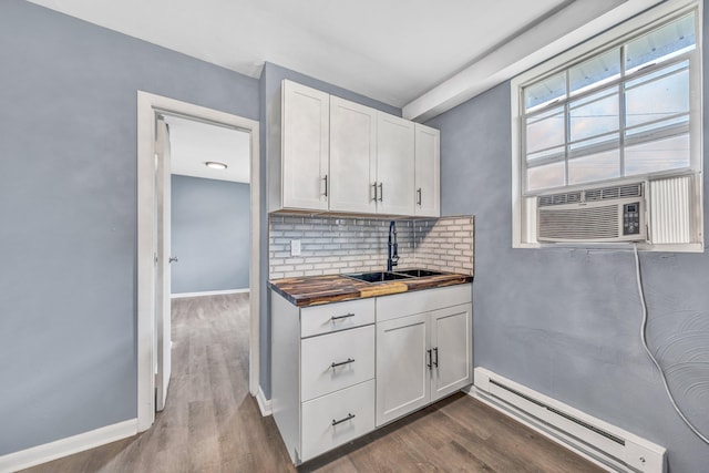 kitchen with a baseboard radiator, a sink, backsplash, white cabinetry, and baseboards