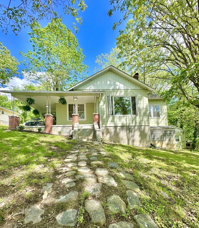 view of front of property featuring covered porch, board and batten siding, a chimney, and a front yard
