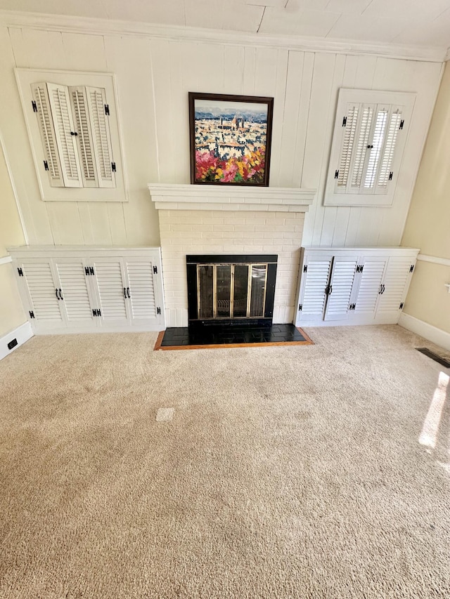 unfurnished living room featuring crown molding, baseboards, a brick fireplace, and carpet floors
