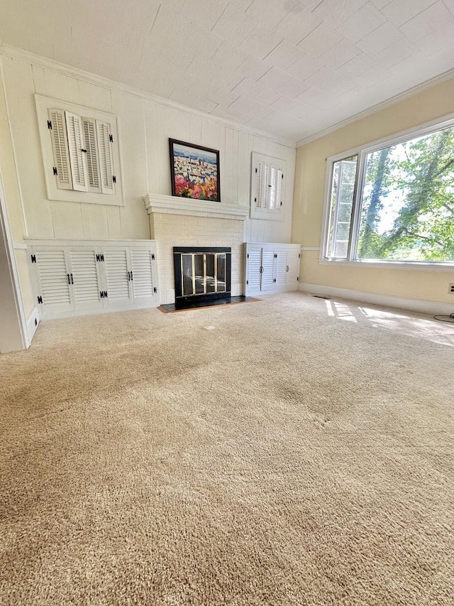 unfurnished living room featuring crown molding, a brick fireplace, and carpet flooring