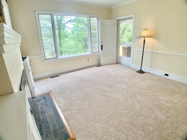 unfurnished living room featuring carpet, baseboards, ornamental molding, visible vents, and a fireplace