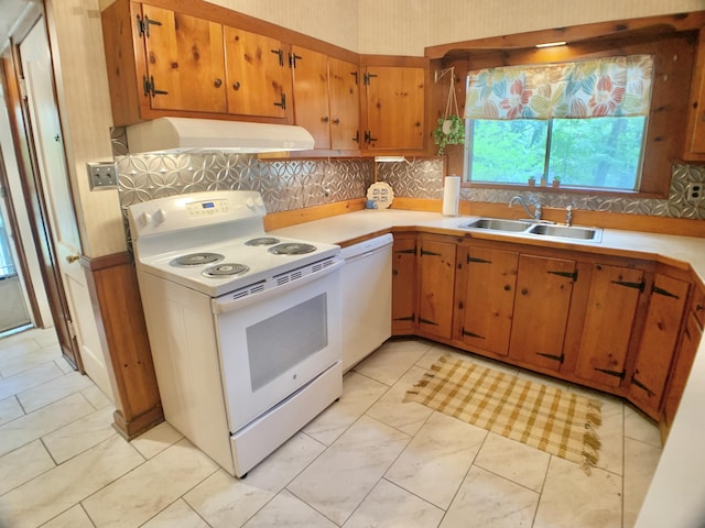 kitchen with under cabinet range hood, white appliances, a sink, light countertops, and tasteful backsplash