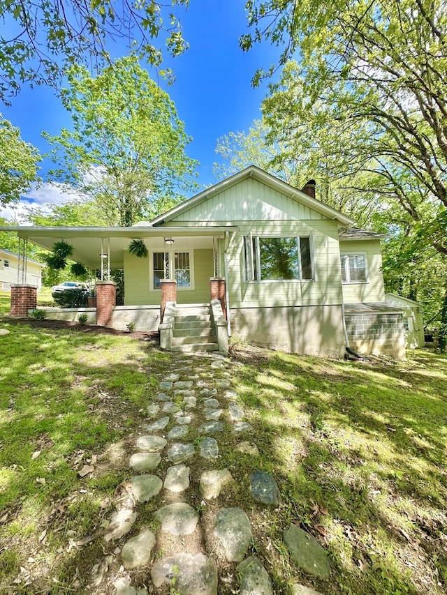 rear view of property featuring a porch, a yard, and a chimney