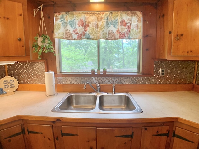 kitchen featuring backsplash, light countertops, and a sink