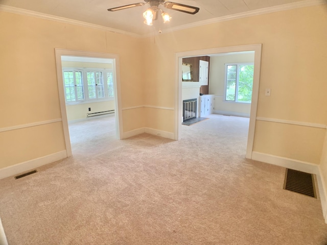 unfurnished room featuring a baseboard heating unit, a wealth of natural light, a fireplace with flush hearth, and visible vents
