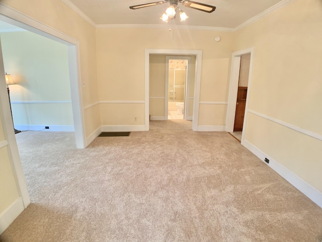 carpeted spare room featuring crown molding, baseboards, and a ceiling fan