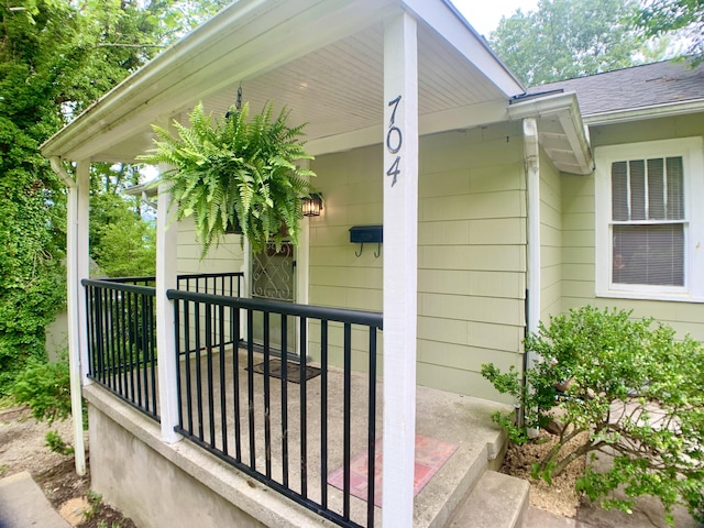 entrance to property with a porch and roof with shingles