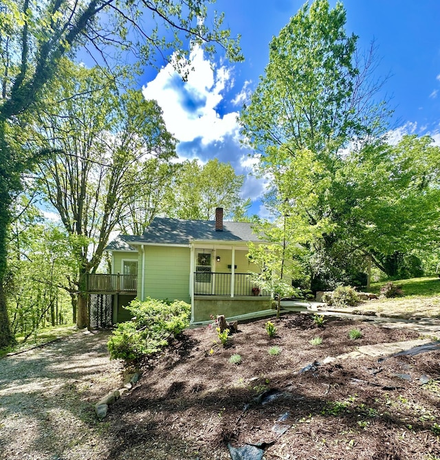rear view of property featuring a porch and a chimney