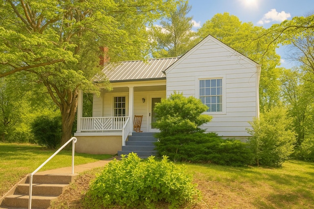 bungalow-style home with a porch, stairs, a front lawn, and metal roof