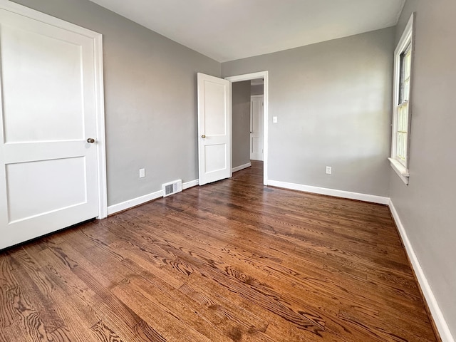 unfurnished bedroom with dark wood-type flooring and baseboards