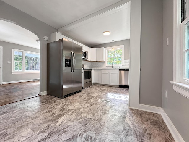 kitchen featuring appliances with stainless steel finishes, a sink, plenty of natural light, and arched walkways
