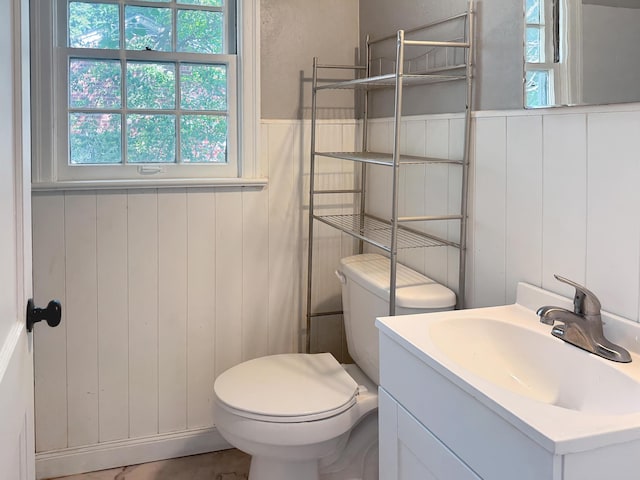 half bath with toilet, vanity, and wainscoting