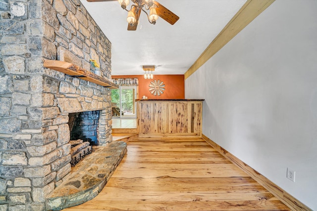 interior space with baseboards, ceiling fan, wood finished floors, and a fireplace