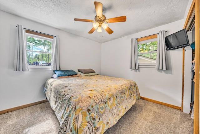 carpeted bedroom with baseboards, a textured ceiling, and multiple windows