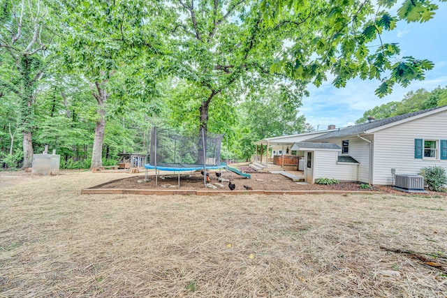 view of yard with central AC and a trampoline