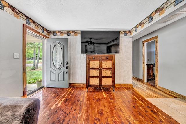 entrance foyer with baseboards, a textured ceiling, and hardwood / wood-style floors
