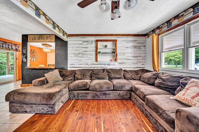 living room featuring a textured ceiling, wood walls, ceiling fan, and hardwood / wood-style flooring