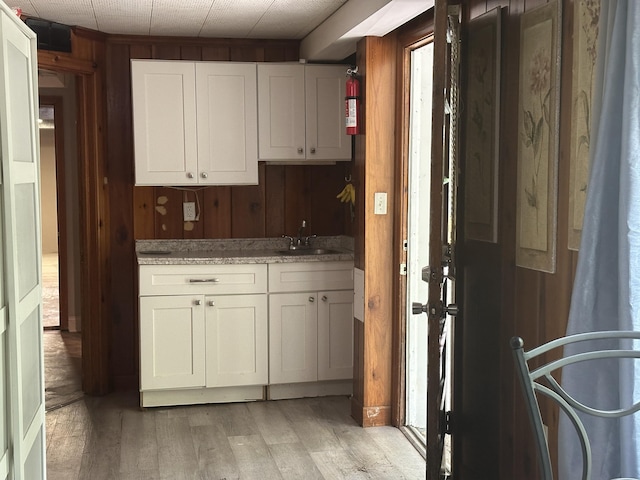 2560 Inglewood Rd SW, Roanoke, VA 24015 - kitchen with a sink, wooden walls, light wood-style floors, white cabinetry, and light stone countertops