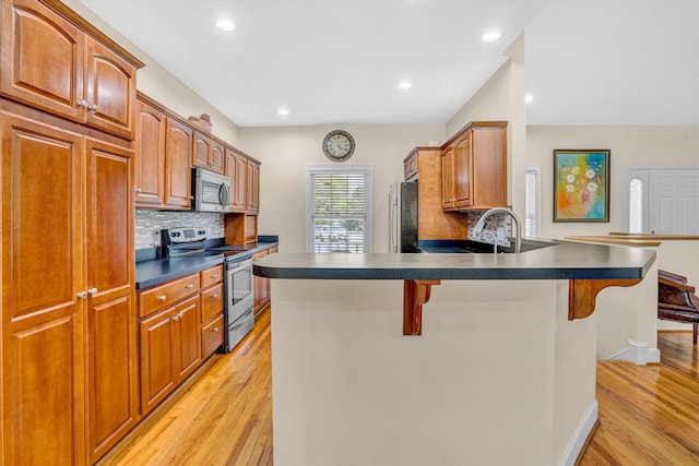 80 Farmers Cir, Moneta, VA 24121 - kitchen with stainless steel appliances, a kitchen bar, light wood finished floors, dark countertops, and a peninsula