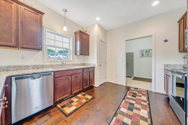 kitchen with light stone countertops, recessed lighting, a sink, dark wood-type flooring, and appliances with stainless steel finishes