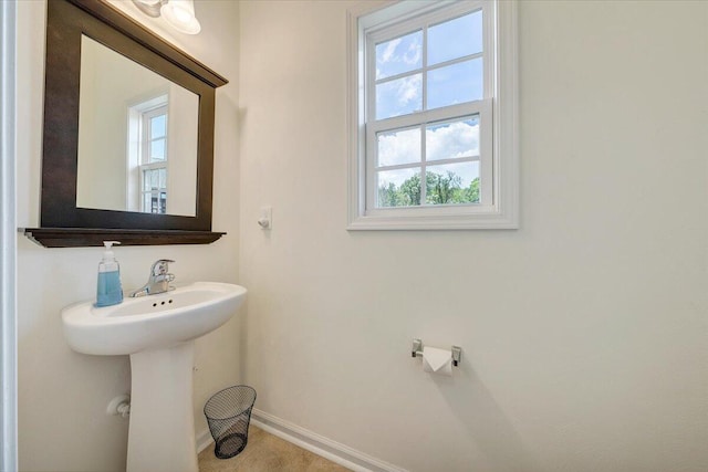 bathroom featuring a sink, baseboards, and a healthy amount of sunlight