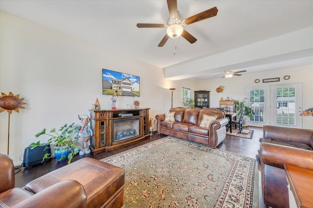 living area with ceiling fan, beamed ceiling, and wood finished floors
