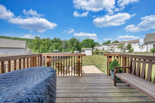 wooden deck featuring a storage shed, a residential view, a yard, an outbuilding, and a fenced backyard