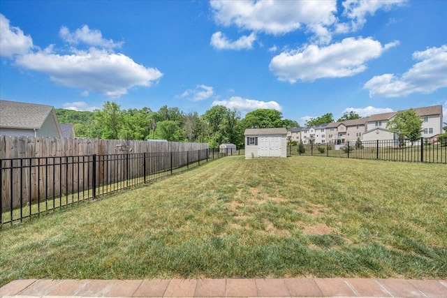 view of yard featuring a storage unit, a fenced backyard, an outbuilding, and a residential view