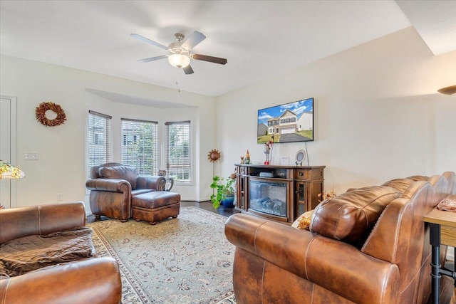 living room with wood finished floors, ceiling fan, and a glass covered fireplace