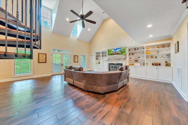 living area with ceiling fan, a fireplace, high vaulted ceiling, french doors, and dark wood-type flooring