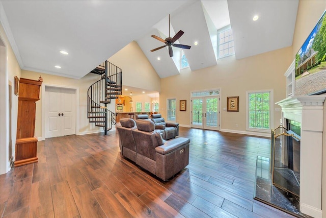 living room with stairs, a glass covered fireplace, wood finished floors, high vaulted ceiling, and a ceiling fan