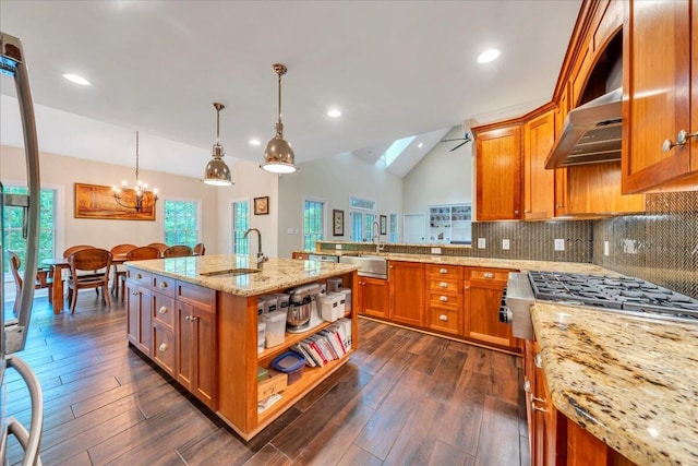 kitchen featuring a sink, light stone counters, brown cabinetry, and lofted ceiling