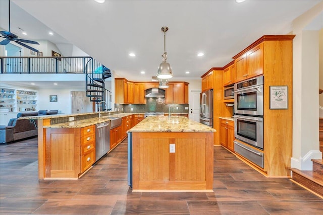 kitchen featuring wall chimney range hood, stainless steel appliances, open floor plan, a peninsula, and a warming drawer
