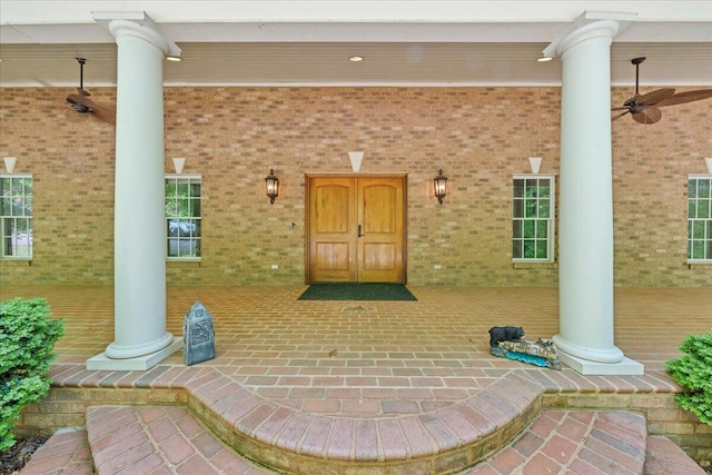 entrance to property with brick siding and a ceiling fan