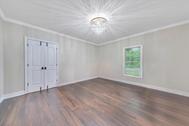 empty room featuring crown molding, baseboards, a chandelier, and dark wood-style floors