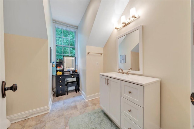 bathroom with baseboards, vaulted ceiling, and vanity