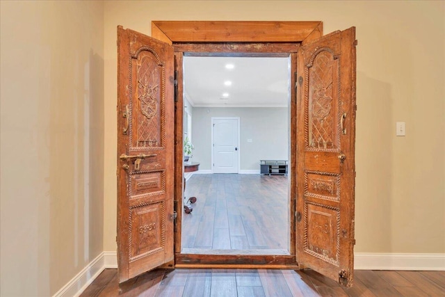 doorway with baseboards, ornamental molding, and wood finished floors