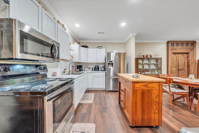kitchen featuring visible vents, appliances with stainless steel finishes, a sink, ornamental molding, and butcher block countertops