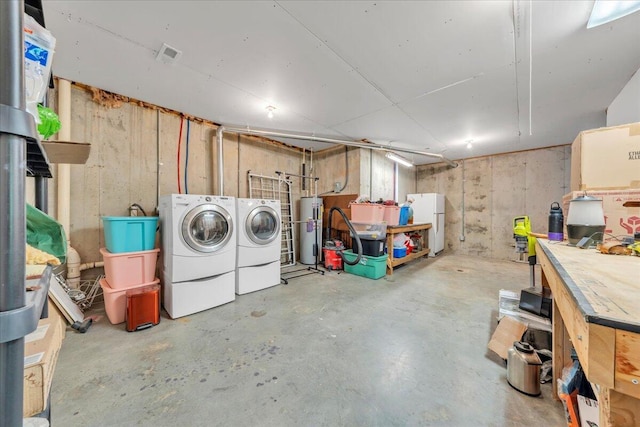 below grade area featuring water heater, freestanding refrigerator, and washing machine and clothes dryer