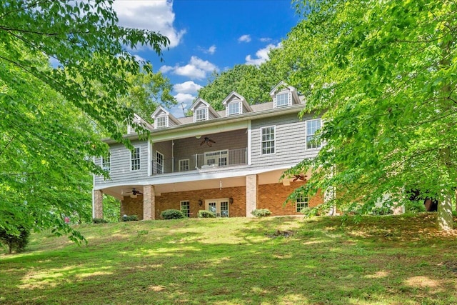 back of house with brick siding, a balcony, french doors, a ceiling fan, and a yard